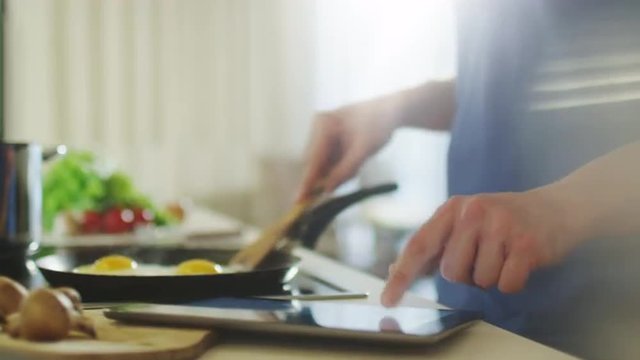Man is Using Tablet PC While Preparing Food