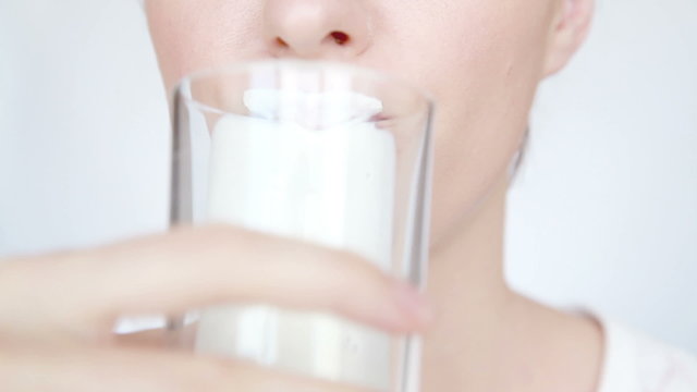 Woman drinks milk and lick off white mustache