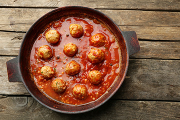 Pan with meat balls in tomato sauce, on wooden background