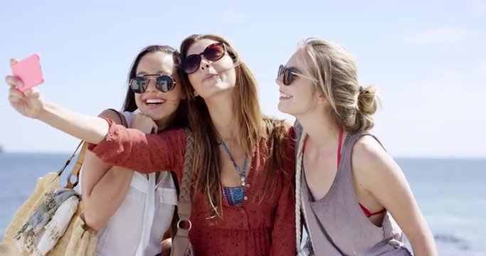 Teenage girls taking selfie pouting at beach on summer vacation