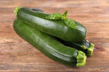 Fresh zucchini with basil on wooden table close up