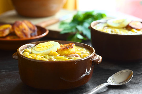 Ecuadorian soup Fanesca, traditionally eaten at Easter prepared from legumes, gourd, pumpkin, milk, salt cod (Selective Focus, Focus on the front of the egg and plantain on top of meal)