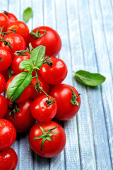 Fresh cherry tomatoes with basil on wooden table close up