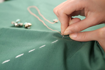 Closeup hands of seamstress at work with cloth fabric