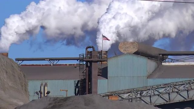 Global warming is suggested by shots of a steel mill belching smoke into the air.