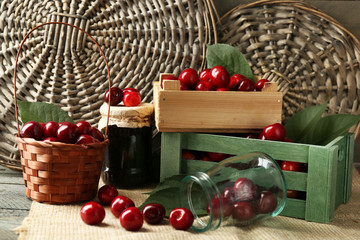 Sweet cherries with green leaves  in basket and wooden boxes, on wooden background