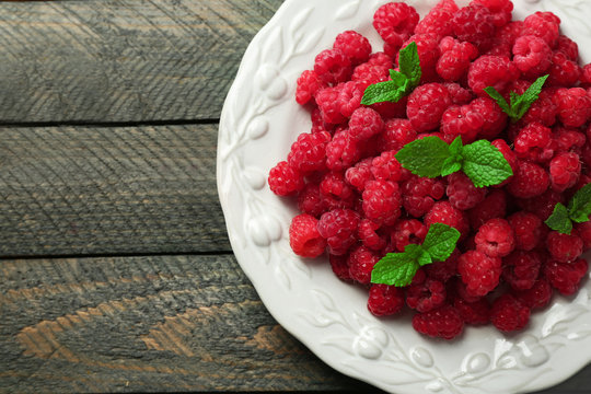 Sweet raspberries on plate on wooden  background