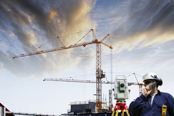 surveyor with measuring instrument and construction site