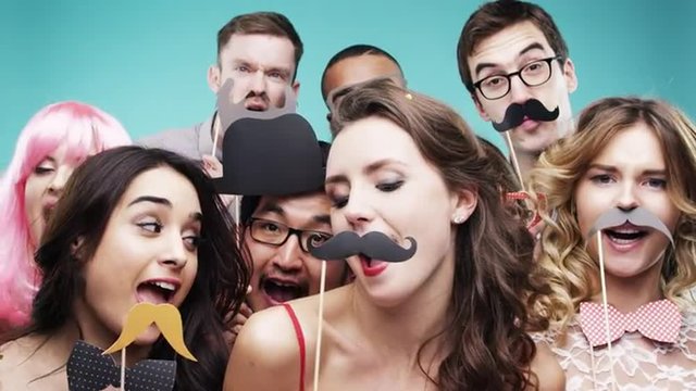 Multi racial group of funny people celebrating slow motion party photo booth 