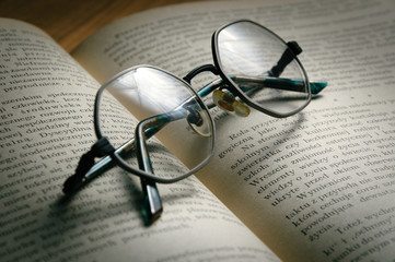 Pair of glasses lying on an open book