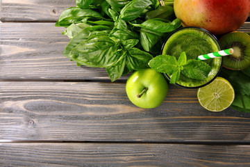 Green healthy juice with fruits and herbs on wooden table close up