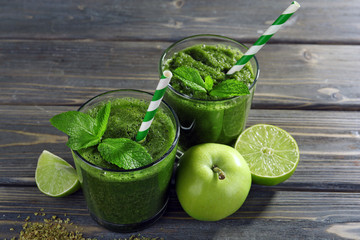 Green healthy juice with fruits and mint on wooden table close up