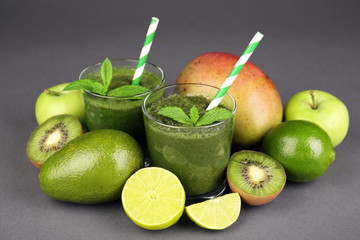 Green healthy juice with fruits and mint on gray background