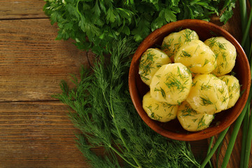 Boiled potatoes with greens in bowl on table close up