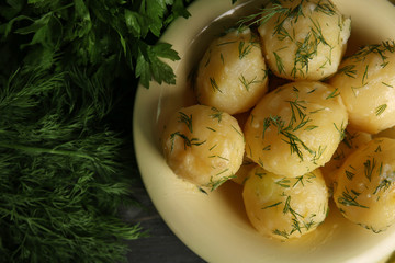 Boiled potatoes with greens in bowl on table close up