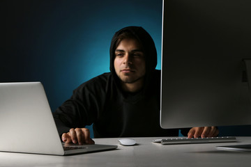 Hacker with computer and laptop on dark background