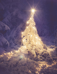 beleuchteter Weihnachtsbaum in verschneitem Wald im Vintage-Stil