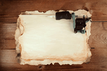 Machine for tattoo with old paper on table close up
