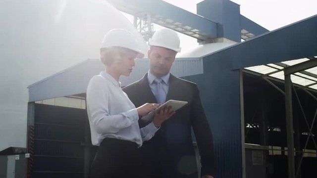 Managers in Hard Hats are Talking and Using Tablet PC in Industrial Environment