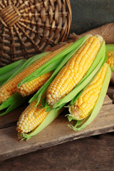 Fresh corn on cobs on wooden table, closeup