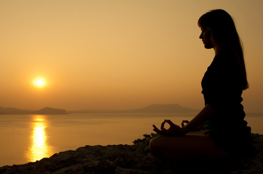 Meditation in lotus position at sunrise on seaside