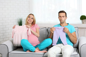 Obraz premium Young pregnant woman with husband on sofa in room