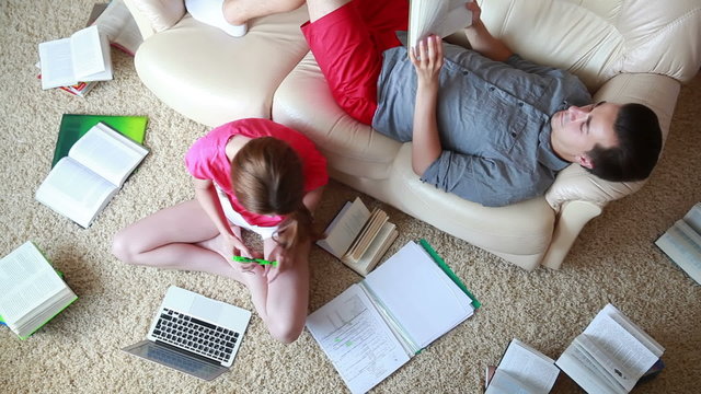 Boy and girl with books and laptop are learning at home.