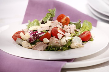 delicious salad with tuna and cashew nuts on a white plate 