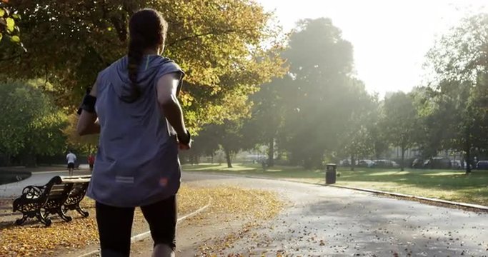 Runner woman running in park exercising outdoors fitness tracker wearable technology