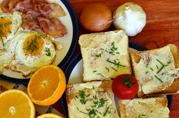 Rustic breakfast - roasted bread with butter and chives, fried eggs and bacon.