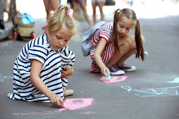 Happy active children drawing with chalk on asphalt