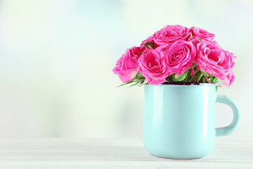 Beautiful roses in mug on bright background