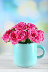 Beautiful roses in mug on bright background