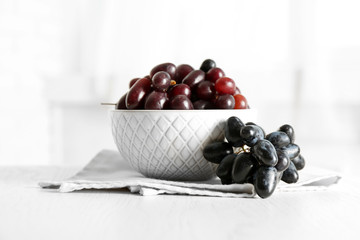 Fresh ripe grapes in bowl on wooden table