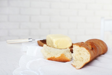 Broken baguette and butter on light background