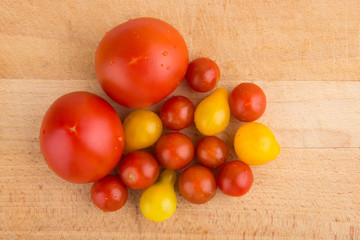 Red and yellow cherry tomatoes on a wooden cutting board