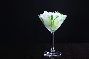 Glass of cocktail with ice on dark background