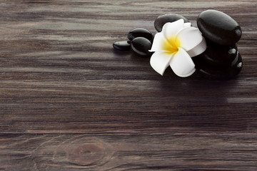 Obraz na płótnie Canvas Wet spa stones with flower on wooden background