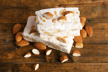 Sweet nougat with almonds on wooden background