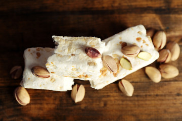 Sweet nougat with pistachios on wooden background