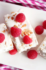 Sweet nougat with nuts and raspberries on plate close up