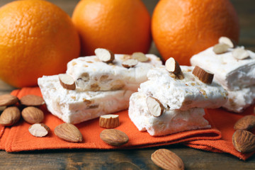 Sweet nougat with almonds and oranges on table close up