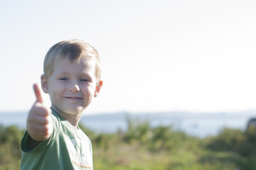 Happy cheerful boy shows thumb up