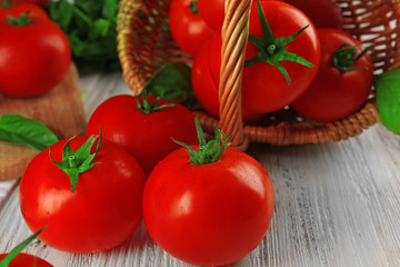 Red tomatoes in basket on wooden background