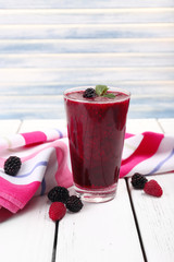 Glass of fresh berry cocktail with napkin on light background