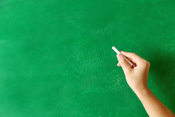 Naklejka premium Female hand writing on blackboard with chalk, close up