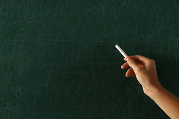 Female hand writing on blackboard with chalk, close up
