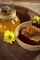 Obraz na płótnie Canvas Pot of honey, honeycomb and dipper in bowl on sackcloth