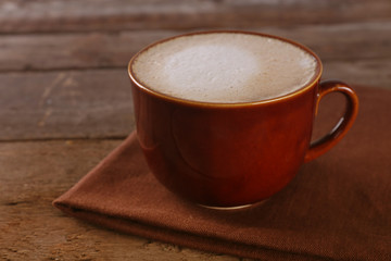Cup of coffee on napkin on wooden background
