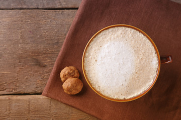 Cup of coffee and biscuits on napkin on wooden background